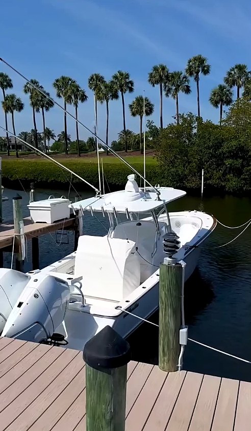 White center console with twin outboards tied up at a Jupiter dock under the palms